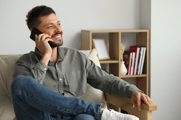 Wall Mural - Happy man talking on smartphone at home