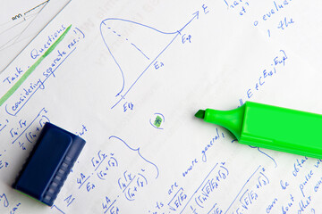 Paper with written mathematical calculations and green highlighter, top view