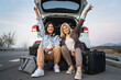 © Miljan Živković - two women mature caucasian female friends sit by the car automobile while parked by the road taking a brake talk in day real people travel vacation copy space happy smile celebrate