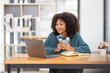 © David - Cute african american female student wearing headphones with afro dreadlocks, studying remotely from home, using a laptop, taking notes on notepad during online lesson, e-learning concept,