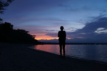 Wall Mural - Woman enjoy dramatic sunset at pemuteran beach, Bali, Indonesia.