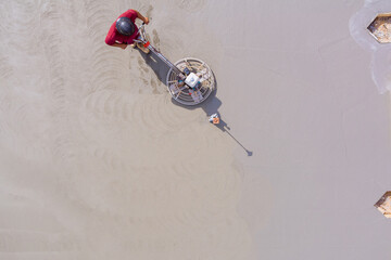 Wall Mural - Worker polishing and leveling cement screed floor on construction site