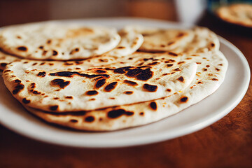 Indian naan breads lie on a wooden table with delicious Indian food in the background, generative AI