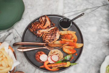 Grilled chicken breast steak in different variations with herbs, vegetables, French fries and sauce on table. Concept of  barbecue lunch or diner. Healthy food, culinary eating and meal.