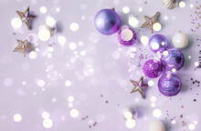 Christmas Or New Year's Flat Lay Composition Of Various Decorative Elements, Sparkles And Christmas Toys In Purple Tones With Bokeh Lights On A Lilac Background. Top View. Copy Space