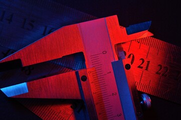 Wall Mural - caliper and metal rulers illuminated in red and blue. close-up