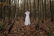 © Milou Dirks - Lonely holy white communion or wedding dress hanging on wash line in forest in art concept