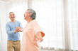 © artitwpd - Romantic and cheerful Asian well-being senior couple enjoy dancing and holding hands to music together with smiles and happiness in the living room. Senior retirement activity at home.