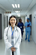 © wavebreak3 - Vertical portrait of smiling asian female doctor in hospital corridor, copy space
