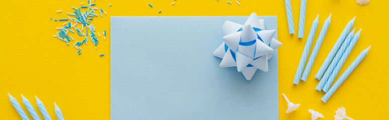Wall Mural - top view of empty greeting card with candles and sprinkles on yellow background, banner.