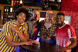 © Wavebreak Media - Portrait of four diverse male and female friends smiling to camera at a bar