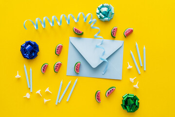 Wall Mural - Top view of festive candles near sweets and envelope on yellow background.