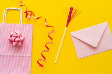 Wall Mural - Top view of shopping bag near serpentine and envelope on yellow background.