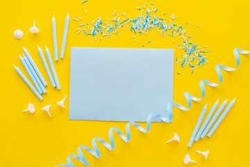 Wall Mural - Top view of empty greeting card near candles and blue serpentine on yellow background.