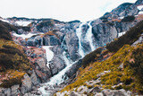 A beautiful landscape with a large mountain waterfall and water running from the stone rocks