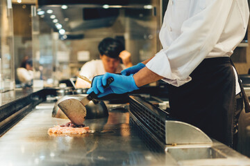 Wall Mural - Hand of man take cooking of meat with vegetable grill, Chef cooking wagyu beef in Japanese teppanyaki restaurant