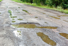 Potholes On The Road With Stones On The Asphalt. The Asphalt Surface Is Destroyed On The Road. Bad Condition Of The Road, Needs Repair. Construction And Repair Of Roads