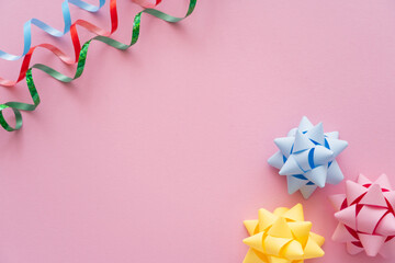 Wall Mural - Top view of colorful serpentine and gift bows on pink background.