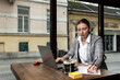 © Srdjan - Young business person owner of restaurant or cafeteria bar calculating year tax and profit earnings on the laptop. Freelancer working in the coffee shop on new project.