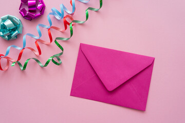 Wall Mural - Top view of envelope near serpentine and gift bows on pink background.