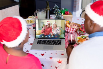 Canvas Print - Senior african american couple having christmas video call with senior caucasian couple