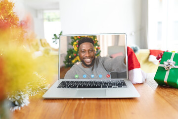 Poster - African american man having christmas video call on laptop screen
