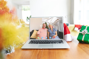 Poster - Happy caucasian couple having christmas laptop video call on table