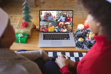 Poster - African american family with santa hats having video call with happy diverse friends