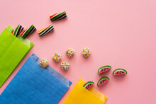 Top View Of Sweet Candies And Paper Bags On Pink Background.