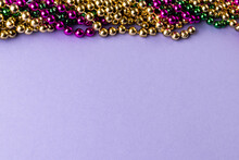 Composition Of Colourful Mardi Gras Beads On Lilac Background With Copy Space