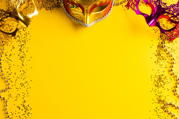 Wall Mural - composition of colourful mardi gras beads and carnival masks on yellow background with copy space