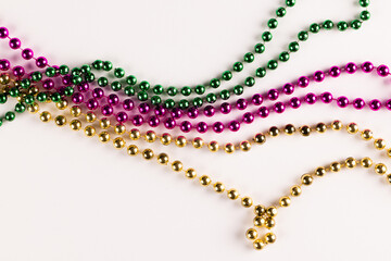 Wall Mural - Composition of colourful mardi gras beads on white background with copy space