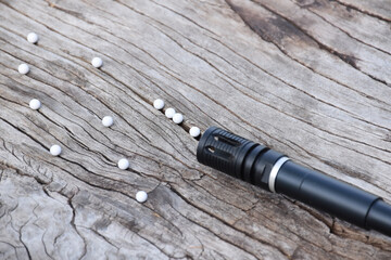 Wall Mural - BB gun or airsoft gun muzzle and white bullets on wooden plank, soft and selective focus.