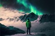 canvas print picture - une personne seule dans la neige regarde les aurores boréales au dessus des montagnes enneigées
