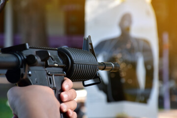 Wall Mural - Airsoft Gun or BB Gun holding in hands of shooter while aiming to the destination target at the bb gun or airsoft gun training camp, soft and selective focus, concept for freetimes and outdoor hobby.