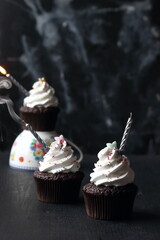 Wall Mural - Cupcakes with candles on a black background