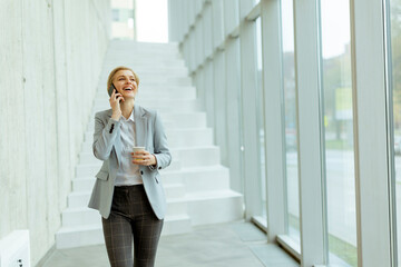 Businesswoman using mobile phone on modern office hallway