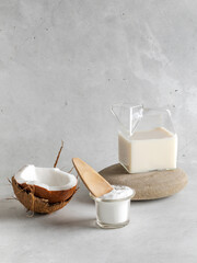 Sticker - Dry coconut milk in a glass bowl in composition with natural coconut and drinking coconut milk on stone closeup