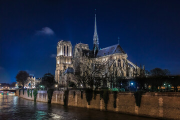 Wall Mural - Illuminated Notre Dame de Paris Cathedral with the spire, before the fire at night, world most famous Gothic Roman Catholic cathedral in Paris, France