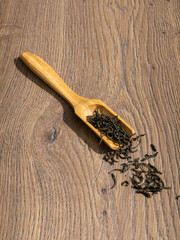 Canvas Print - Black tea spills out of a wooden spoon on wooden background