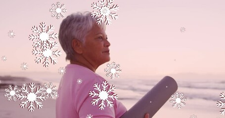 Sticker - Animation of christmas snow falling over senior biracial woman on beach