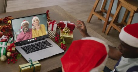 Wall Mural - Diverse couple having christmas video call with senior diverse couple