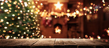 Christmas Tree With Illumination Near The Fireplace. Blurred Background With Illumination Lights On Wooden Background