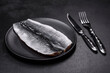 Marinated fillet with spices and herbs of sea herring on a black plate