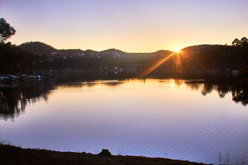 Wall Mural - lake on sunset with sun in the horizont, mountains in the background, lake arareco in creel chihuahua 