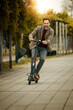 Attractive businessman riding a kick scooter in city