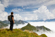 Ein Wanderer schaut auf dem Gehrengrat über den Wolken auf die Gipfel der Alpen, Lech, Österreich