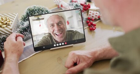 Canvas Print - Caucasian man with christmas decorations having tablet video call with happy caucasian man