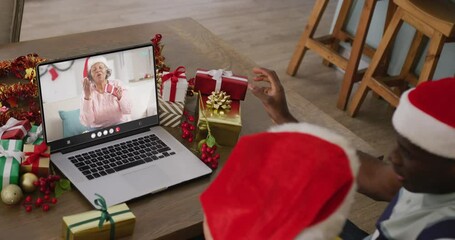 Poster - Diverse couple with santa hats having laptop video call with happy african american woman