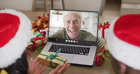 Poster - Diverse couple with santa hats having laptop video call with happy caucasian man